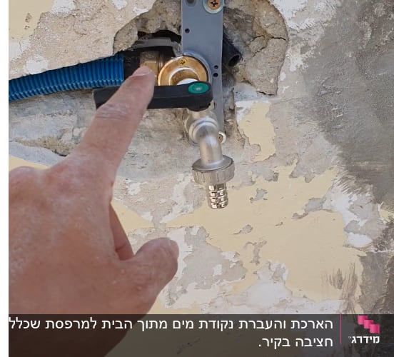 יד מצביעה על ברז מים בקיר עם צינור כחול